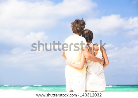 back view of happy couple having fun on the beach
