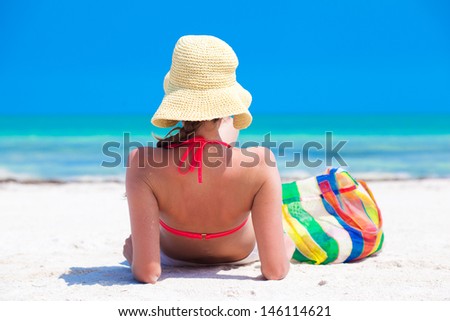 back view of young woman in straw hat and bikini with beach bag. Holbox, mexico