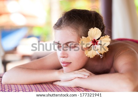 beautiful young woman with yellow flower in hair lying in spa