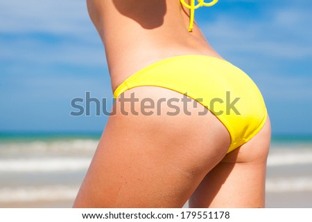 back view of fit young woman in yellow bikini