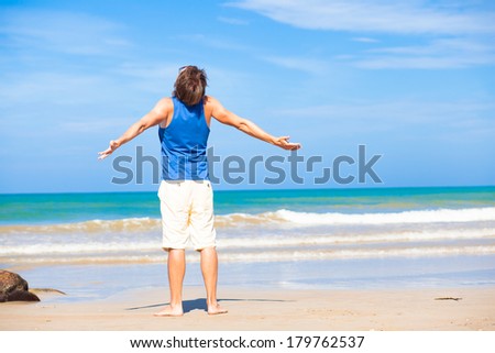 man waving hands at the beach, enjoying his time tanning