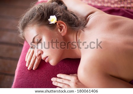 beautiful young woman with flower in hair lying in spa