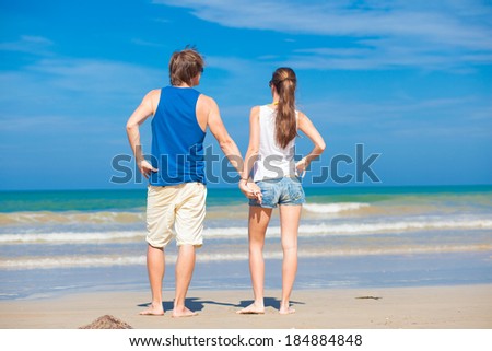 back view of couple holding hands on tropical beach