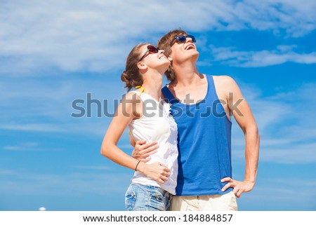 Closeup of happy young couple in sunglasses on beach smiling and looking at sky