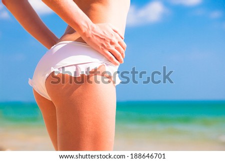 back view of fit young woman\'s bottom in white bikini