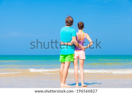 back view of happy young couple hugging at tropical beach