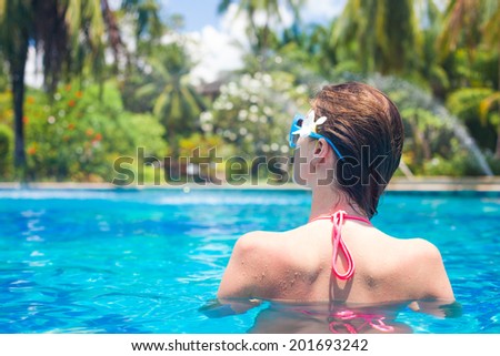 back view of fit woman with flower in hair in luxury spa pool