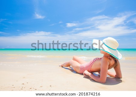 long haired woman in bikini and straw hat bikini on tropical beach