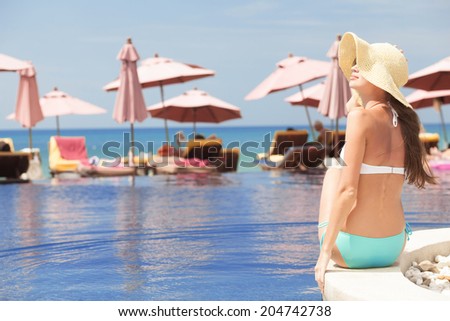 back view of fit woman in straw hat by luxury spa pool