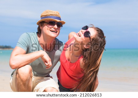 Portrait of happy young couple in sunglasses smiling on beach
