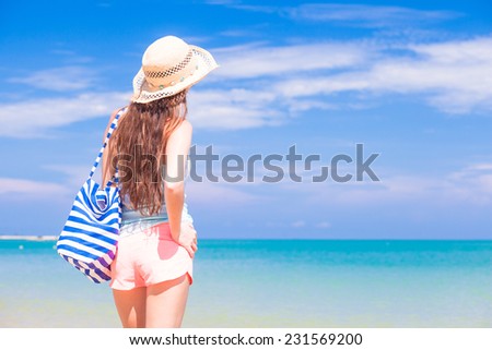 back view of a fit young woman with stripy bag at tropical beach