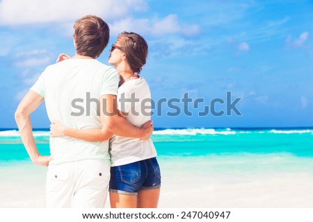 back view of happy couple in sunglasses on the beach