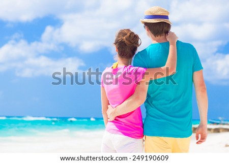 back view of happy couple in sunglasses on the beach
