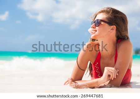 portrait of woman in red swim suit relaxing on tropical beach