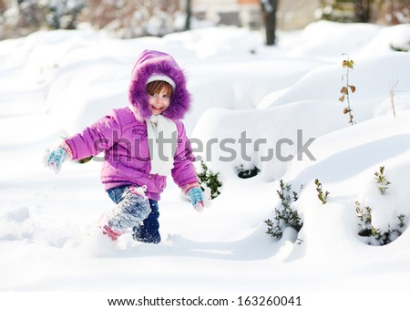 Smiley girl in the snow in purple clothes
