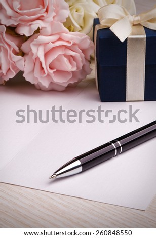 blank card with pen, blue gift box, pink and white roses