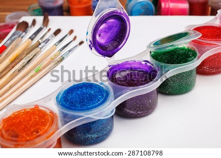 Paint brushes with opened paint buckets with brushes on white sheet  of paper