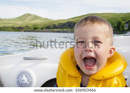 Two kids sitting in the bow of a boat with there life jackets having fun