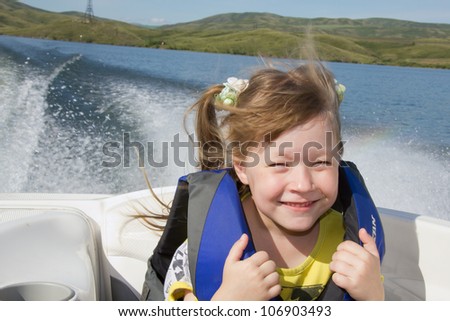 Two kids sitting in the bow of a boat with there life jackets having fun