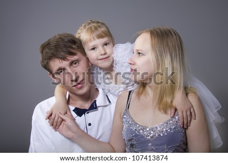 Young European family from three persons - mother, father and daughter. On a gray background