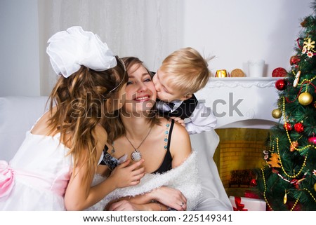 Two children kiss and embrace the gentle mother