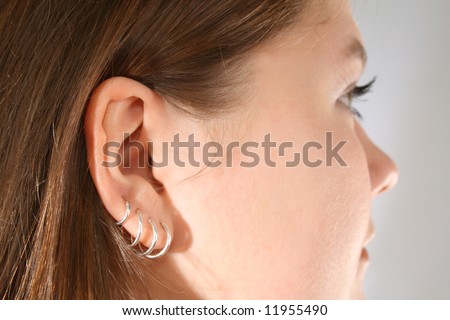 stock photo : Close-up of multiple ear piercings on young girl.