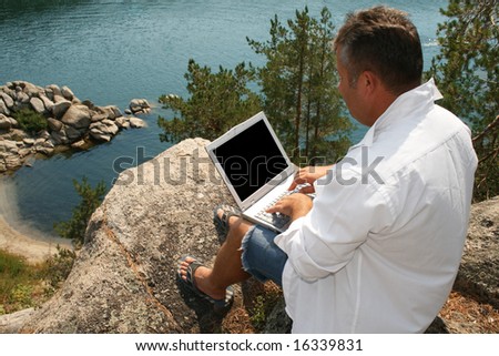 Man working on a laptop on the rocks. With copy space - you can place what you wish on the monitor.