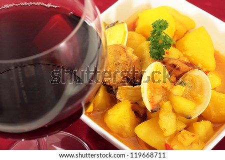 bowl  of boiled potatoes with clams squid and fish accompanied by wine