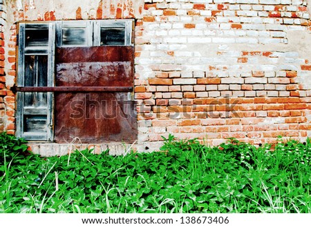 Old metal window and wall with bricks and plants at the bottom