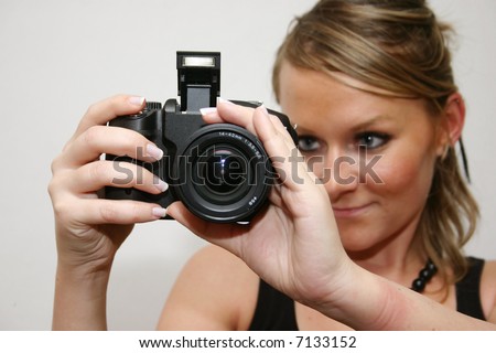 young cute woman looking through her digital camera to find the right focus