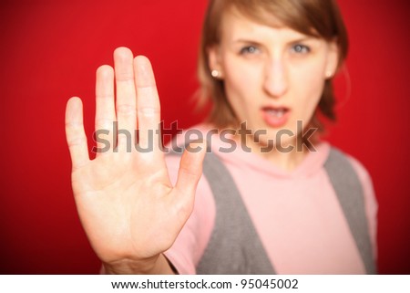 young woman in front of red background saying no shielding with flat hand (focus on hand)