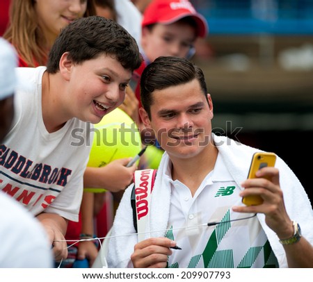 WASHINGTON - AUGUST 1: Milos Raonic (CAN) takes a photo with a fan after defeating Steve Johnson (USA, not pictured) at the Citi Open tennis tournament on August 1, 2014 in Washington DC