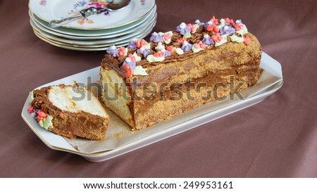 roulade cake with butter cream, decorated with colorful cream flowers