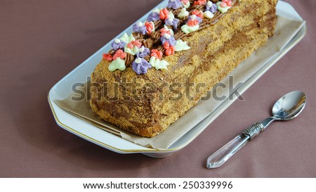 roulade cake with butter cream, decorated with colorful cream flowers
