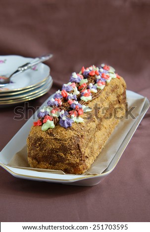 roulade cake with butter cream, decorated with colourful cream flowers