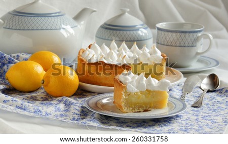 Lemon tart, cake with meringue on the blue floral table cloth