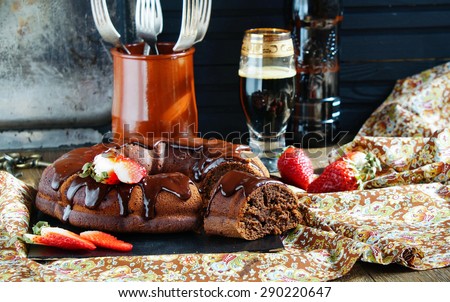 chocolate cake on the base of dark beer with chocolate icing and strawberries - dark rustic style
