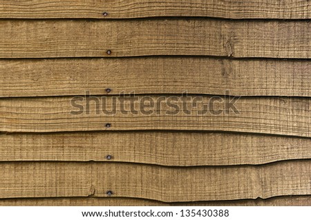 A section of horizontal, overlapped wooden garden fencing.