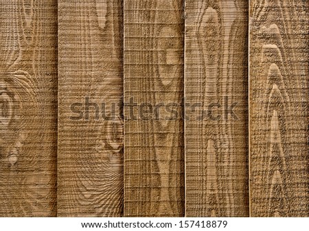 A close up section of wooden garden fencing with vertical, overlapped panels.