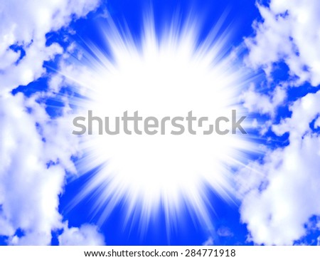A brilliant star burst of light in center of a bright blue sky framed by fluffy white clouds with copy space