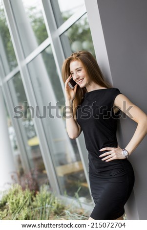 Young woman talking on the phone in front of office