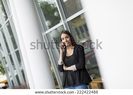 Young woman talking on the phone in front of office