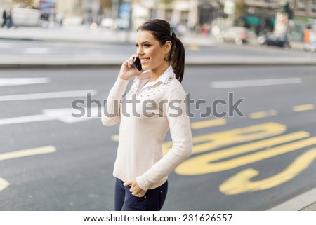 Pretty young woman talking on the mobile phone on the city street