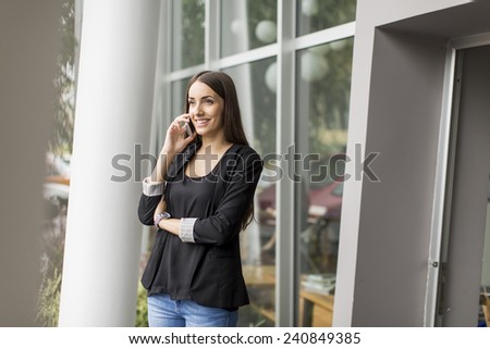 Pretty young woman talking on the phone in front of office