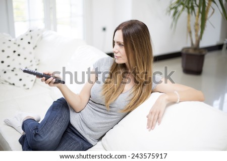 Young woman changing channels with remote control