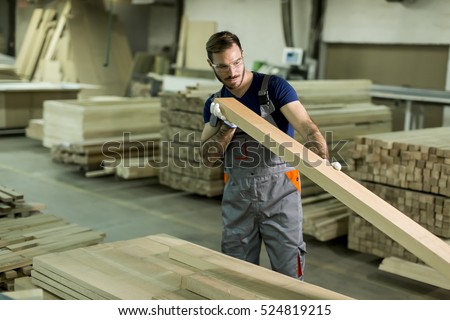 Young worker works in a factory for the production of furniture