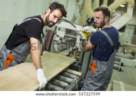 Young male workers work in a factory for the production of furniture