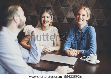 Two women and a man at cafe, talking, laughing and enjoying their time.