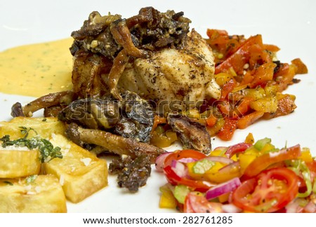 fried fish with glazed mushrooms, cheese sauce and vegetables on the side on white