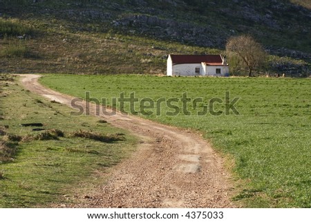 Road to a farmhouse next to a mountain